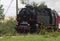 Historic steam locomotive with passenger wagons on rail tracks