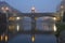 Historical bridge over a river with city lights in the fog in the early morning