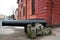 Historical building of red brick in Kronstadt, Russia with the vintage gun in front in winter cloudy day