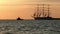 Historical tall ship replica schooner floats past the lighthouse at sea near a smaller towing boat