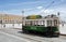 Historical tour tram driving past historical squaare under blue sky at bright day