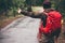 Hitchhiker with red backpack alone on the road