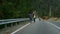 Hitchhikers trekking mountains highway at summer. Couple catch car on roadside.