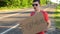 Hitchhiking traveling young adult man displaying Everywhere written sign board pointing thumb up on interstate highway