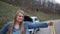 Hitchhiking woman gives a thumbs up to the camera ALT