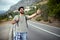 Hitchhiking young traveller man try to catch car on a forest road