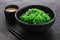 Hiyashi Wakame Chuka seaweed salad with sesame seeds in a black bowl and peanut sauce