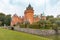 Hjularod is a romantic red castle with tall towers surrounded by a moat