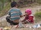 Hmong child eating candy on the dirty ground in Van rocky plateau.