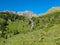 Hochschober - Horses grazing on alpine meadow with scenic view of idyllic waterfall and majestic mountain peak of Hochschober