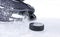 Hockey skate with snow splashes and puck