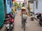 Hoi An, Vietnam - 28 Jul 2019: Woman in traditional vietnamese hat riding bicycle in narrow street