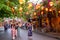 Hoi An, Vietnam. Asian dressed women stroll through an avenue in the tourist attraction, in whose trees hang illuminated lanterns 