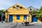 Hoi An, Vietnam - June 2019: man riding scooter next to colorful house in old town