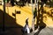 Hoi An, Vietnam - June 2019: Vietnamese woman walking along yellow wall in old town district