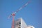 Hoisting tower crane on top of construction skyscraper building over blue sky