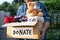 Holding clothing donation box with used clothes and doll at home to support help for poor people in the world