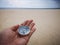 Holding a compass showing the direction point to north and facing the ocean.