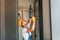 Holding electric drill in hands. Young man working in uniform at construction at daytime