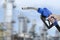 Holding a fuel nozzle against with Oil refinery blurred background