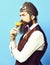 Holding glass of alcoholic beverage in vintage suede leather waistcoat with hat and glasses on red studio background