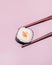 Holding a Maki Sushi Piece with Chopsticks on Pink Background Culinary Gourmet Japanese Food Close Up