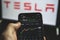 Holding mobile phone with stock market charts of Tesla company shares