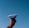 Holding a paper airplane in your hand against the blue sky. White paper airplane