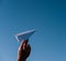 Holding a paper airplane in your hand against the blue sky. White paper airplane