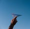 Holding a paper airplane in your hand against the blue sky. White paper airplane