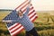 Holding USA flag in hands. Patriotic senior stylish man with grey hair and beard on the agricultural field