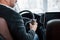 Holds cup with coffee. View from behind of senior businessman in official clothes inside of modern car