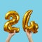 Holds number-shaped balloons forming the number 24