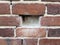 Hole in damaged red brick wall or masonry