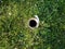 Hole in metal pipe in green grass or lawn