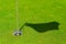 hole on putting green with flag stick and shadow of flag. hole or target point for success concept . copy space for your text.