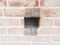 Hole in red brick wall with metal mesh or screen