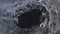 Hole in small iceberg with shiny clear ice surface filled with grains of black sand on diamond beach in southern Iceland.