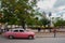 Holguin, Cuba: retro old pink car parked on a street in the city center. Cathedral in Downtown Holguin