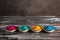 Holi festival. Colored holi powders in a bowl on a dark rustic wooden table. Selective focus