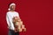 Holiday Ad. Cheerful Young Man Wearing Santa Hat Holding Stack Of Gifts