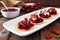 Holiday appetizers with cranberries, goat cheese and pecans on a serving plate, close up table scene against wood