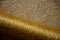 Holiday background of golden sparkly mesh fabric with copy space. Glittering background. Gold thread on beige background.