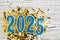 Holiday background Happy New Year 2025. Numbers of year 2025 made by blue candles on festive white wooden background