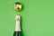 Holiday Bottle of champagne and Christmas toys over green background. Christmas and New Year celebration. Copy space. Bottle with