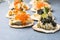 Holiday canapes with red and black caviar, on crackers festive silver Christmas decoration, copy space, selected focus, narrow