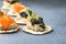 Holiday canapes with red and black caviar, on crackers festive silver Christmas decoration, copy space, selected focus, narrow
