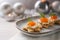 Holiday canapes with red caviar, cream and dill garnish on toasted bread in star shape on a gray plate, festive silver Christmas