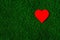 Holiday card: red paper heart lies on a green grass