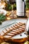 Holiday dish of sliced baked meat with sauce in plate on wooden table served with plate, glasses, bottle of wine, candles, fir